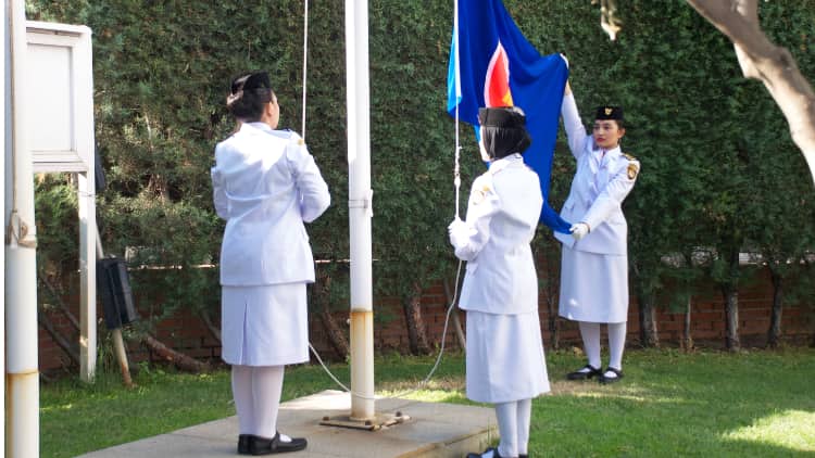 Three young Indonesian women raise the ASEAN flag in the Embassy gardens during the commemoration / Photo: AR